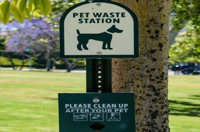 pet waste station installation. Pet waste station installed in a park with a sign encouraging responsible pet waste disposal.
